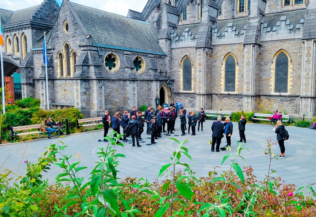 A group of teenage boys dressed in black pants and tops with red ties gather in front of Christ Church Cathedral. One Day in Dublin. MPA Project Travels.